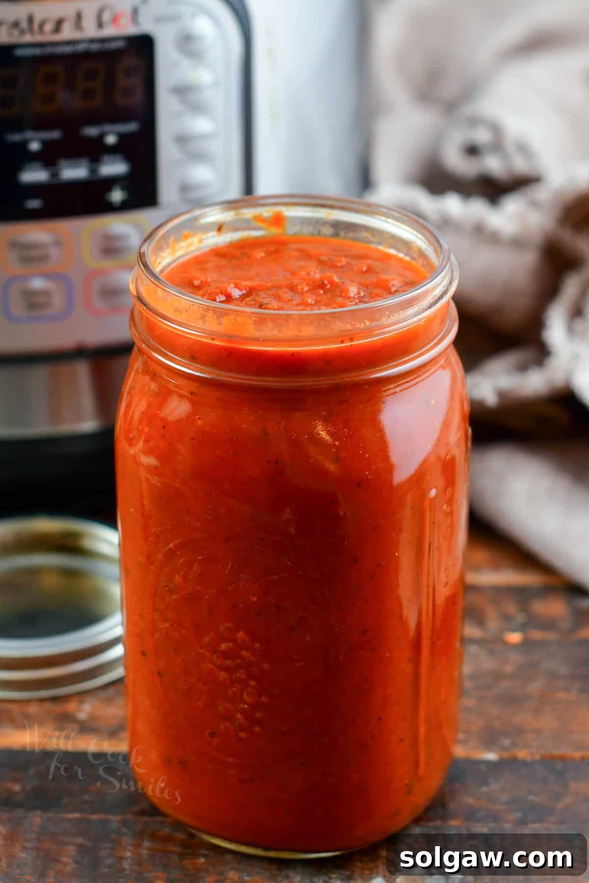 Delicious Instant Pot Spaghetti Sauce in a clear glass jar, perfectly blended and ready to serve, next to the Instant Pot.