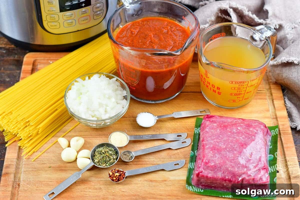 All key ingredients for Instant Pot spaghetti, including ground beef, spaghetti noodles, tomato sauce, onions, garlic, and spices, laid out on a wooden board.