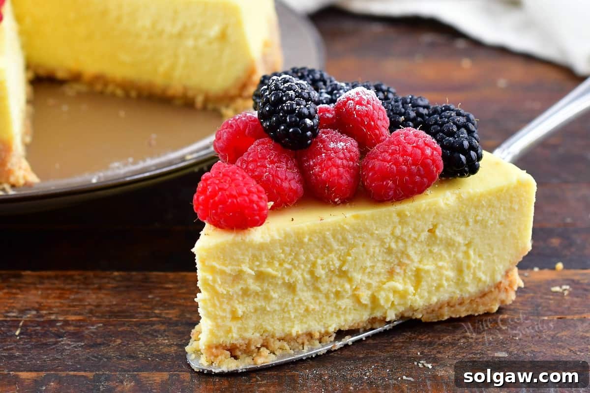 A close-up view of a slice of ricotta cheesecake, topped with a generous portion of fresh berries, highlighting its creamy texture.