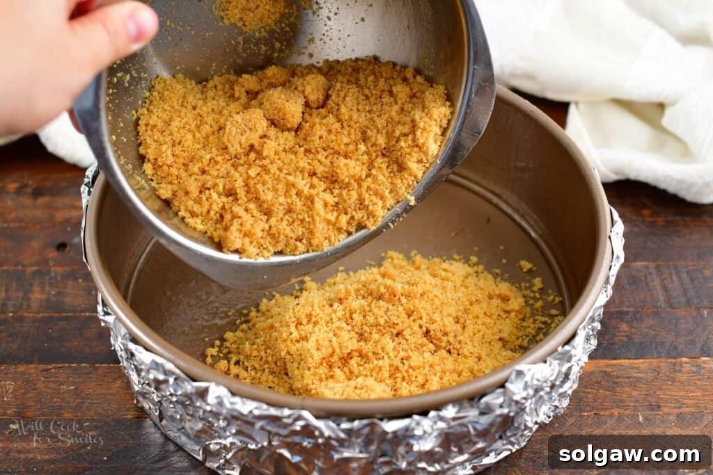 Pressing the biscotti crust mixture into a springform pan to form an even base.
