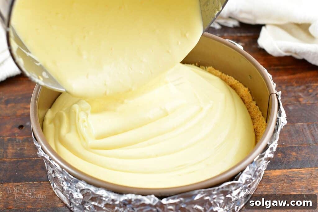 Pouring the smooth cheesecake filling into the prepared springform pan over the biscotti crust.