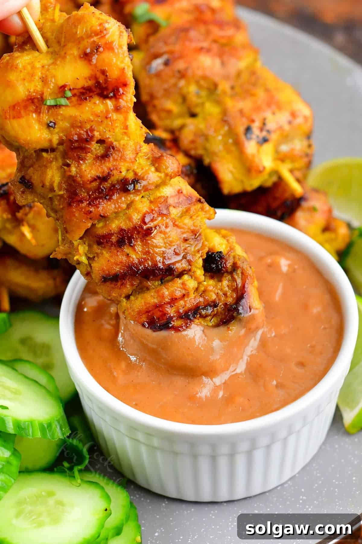 Sizzling Thai Chicken Satay with Velvety Peanut Sauce 2 Tender Thai Chicken Satay skewers dipped in creamy homemade peanut sauce, garnished with fresh cilantro.