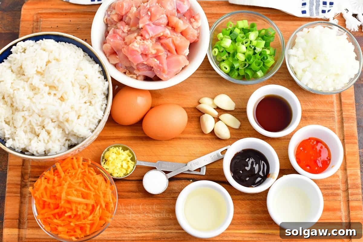 Close-up of fresh ingredients for Thai fried rice including chicken, vegetables, and sauces.