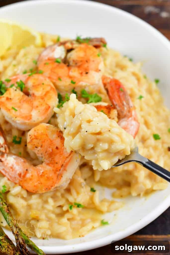 A person scooping a generous portion of creamy lemon risotto from a white bowl, showcasing its rich texture.