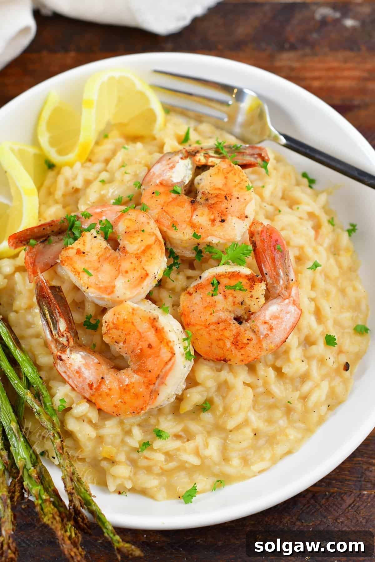 A close-up of creamy lemon risotto topped with perfectly seared lemon pepper shrimp.