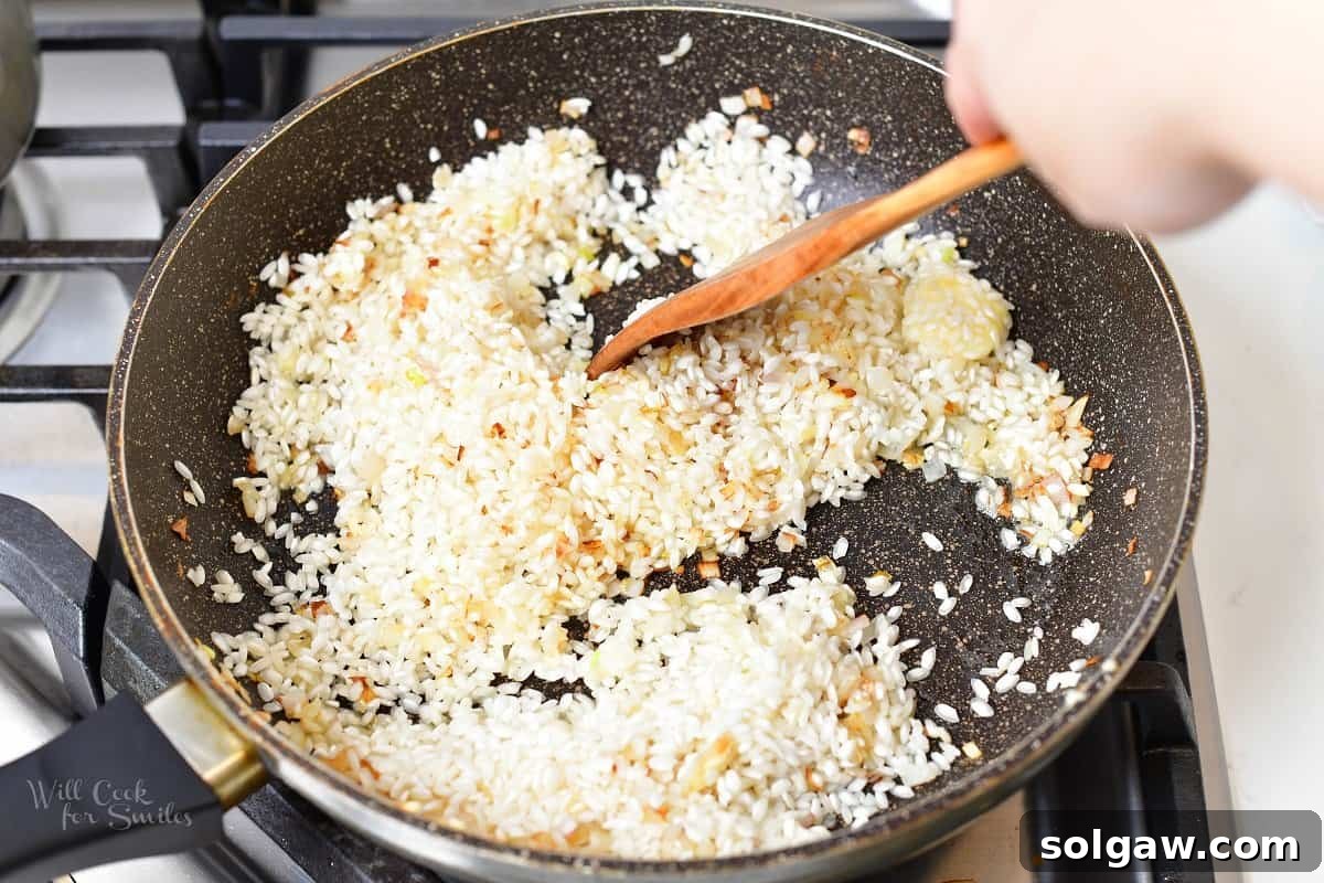 Minced garlic being added to sautéed shallots in a pan, releasing its fragrant aroma for the risotto base.