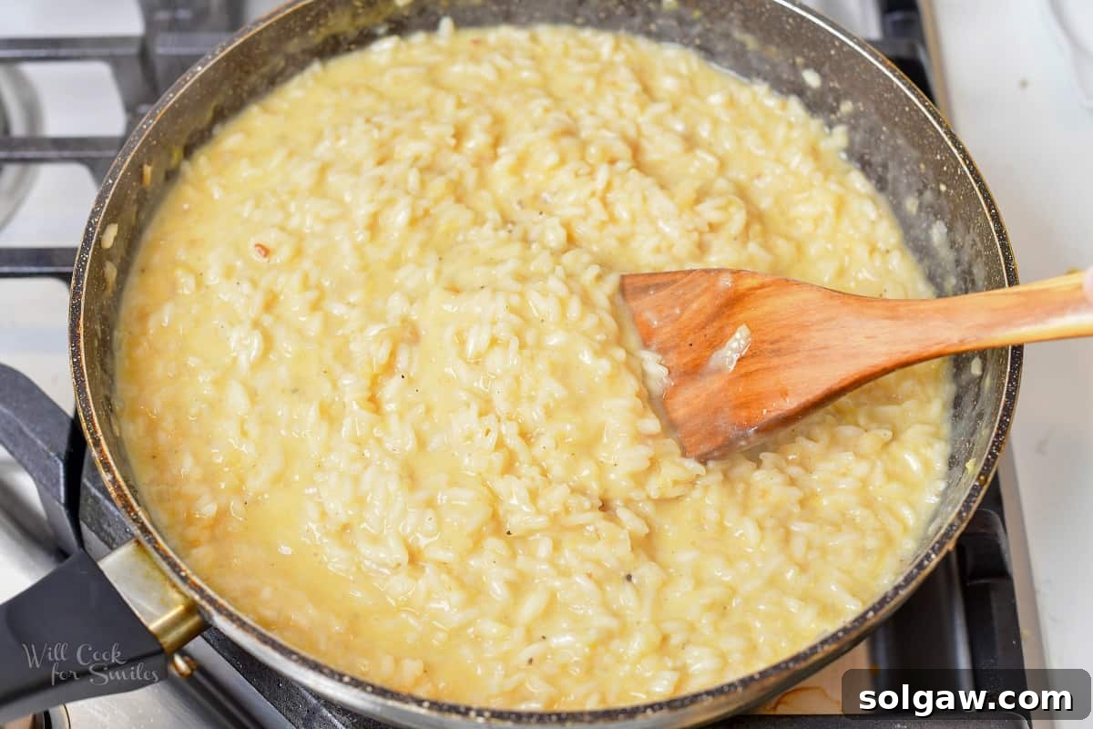 The process of stirring and absorbing broth into the risotto, showing its gradual transformation into a creamy consistency.
