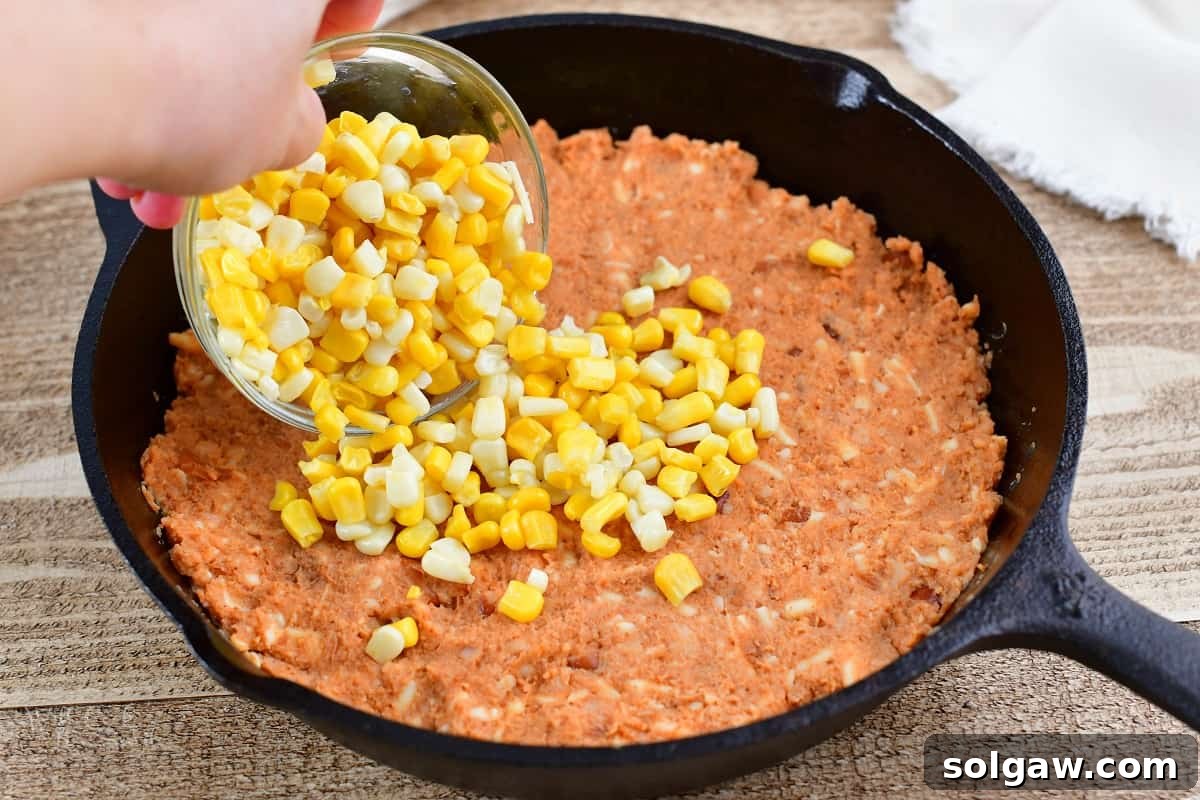 spreading corn over refried bean mixture