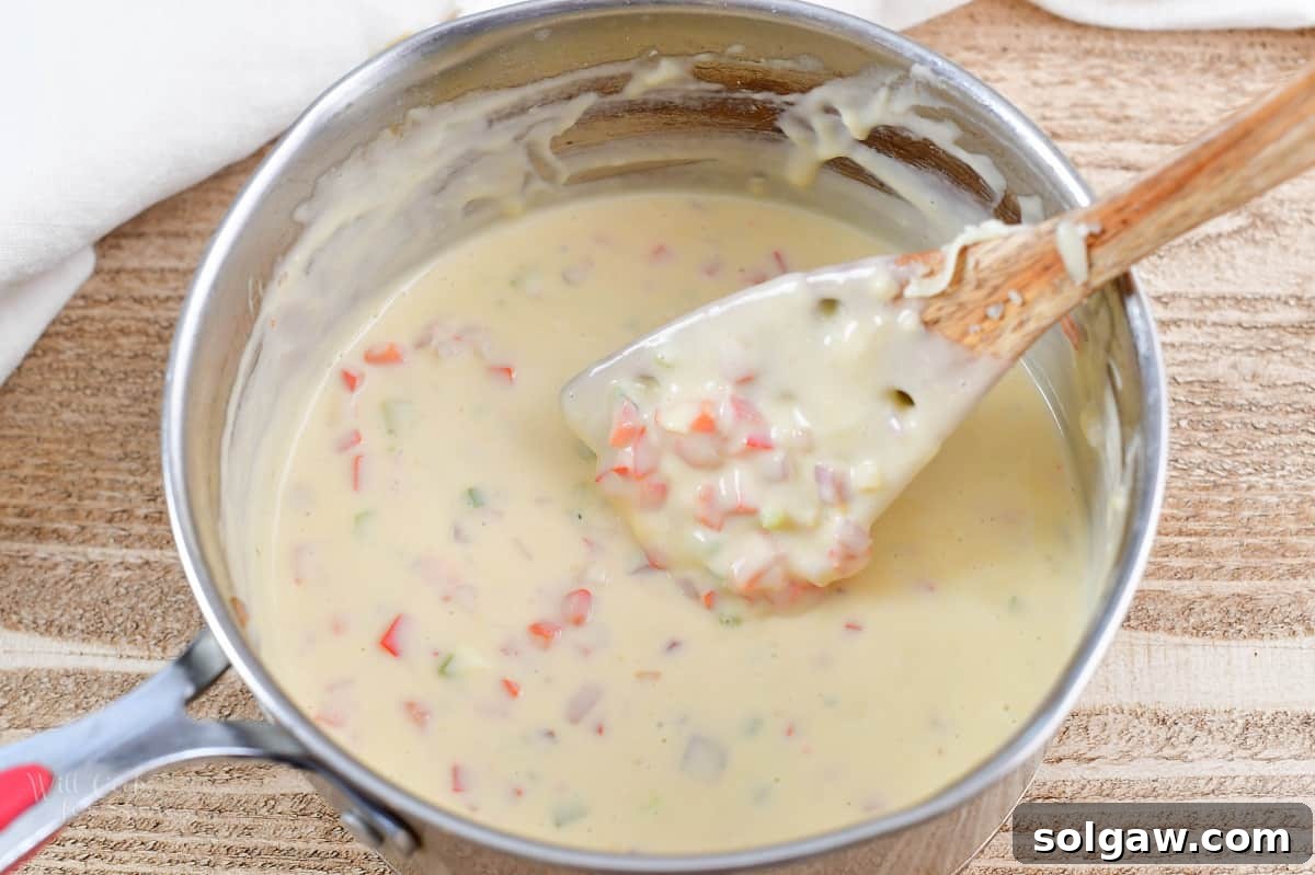 stirring queso dip in a pot with a wooden spoon