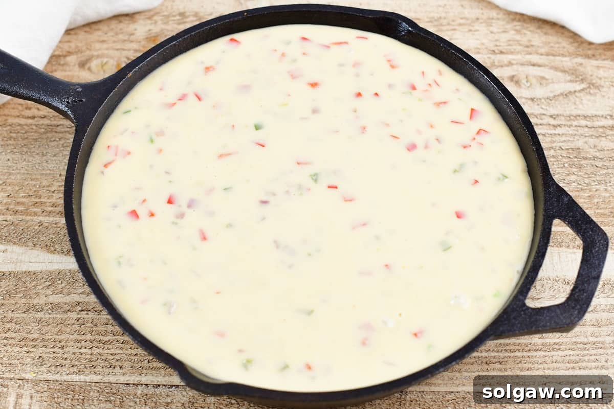 queso poured over refried bean mixture in a skillet