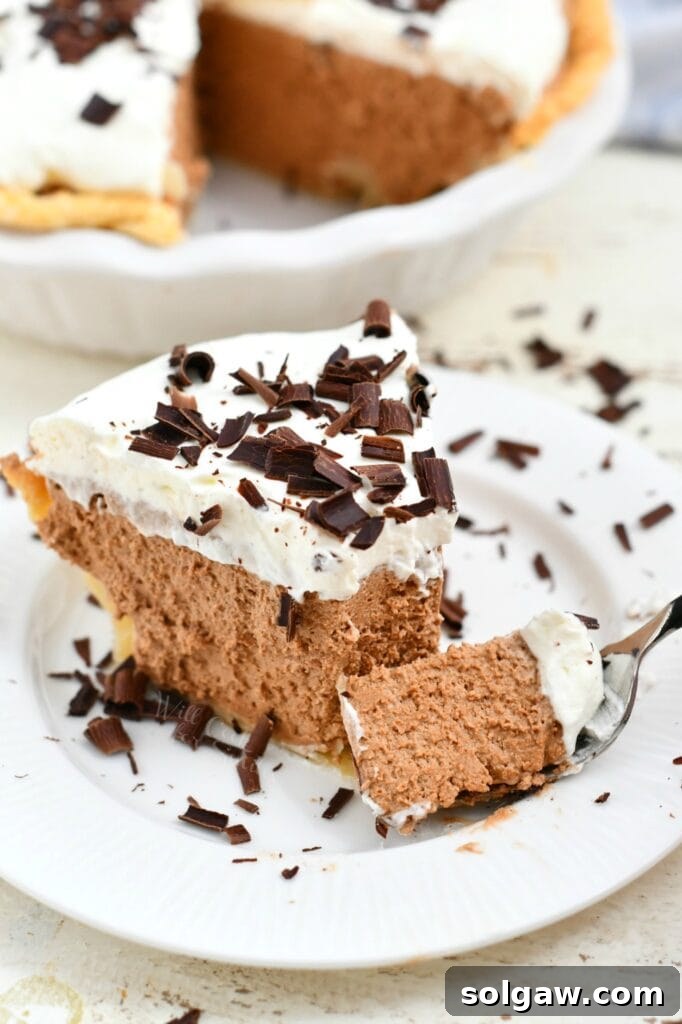 forkful of creamy chocolate French silk pie topped with whipped cream and chocolate shavings, highlighting the smooth texture