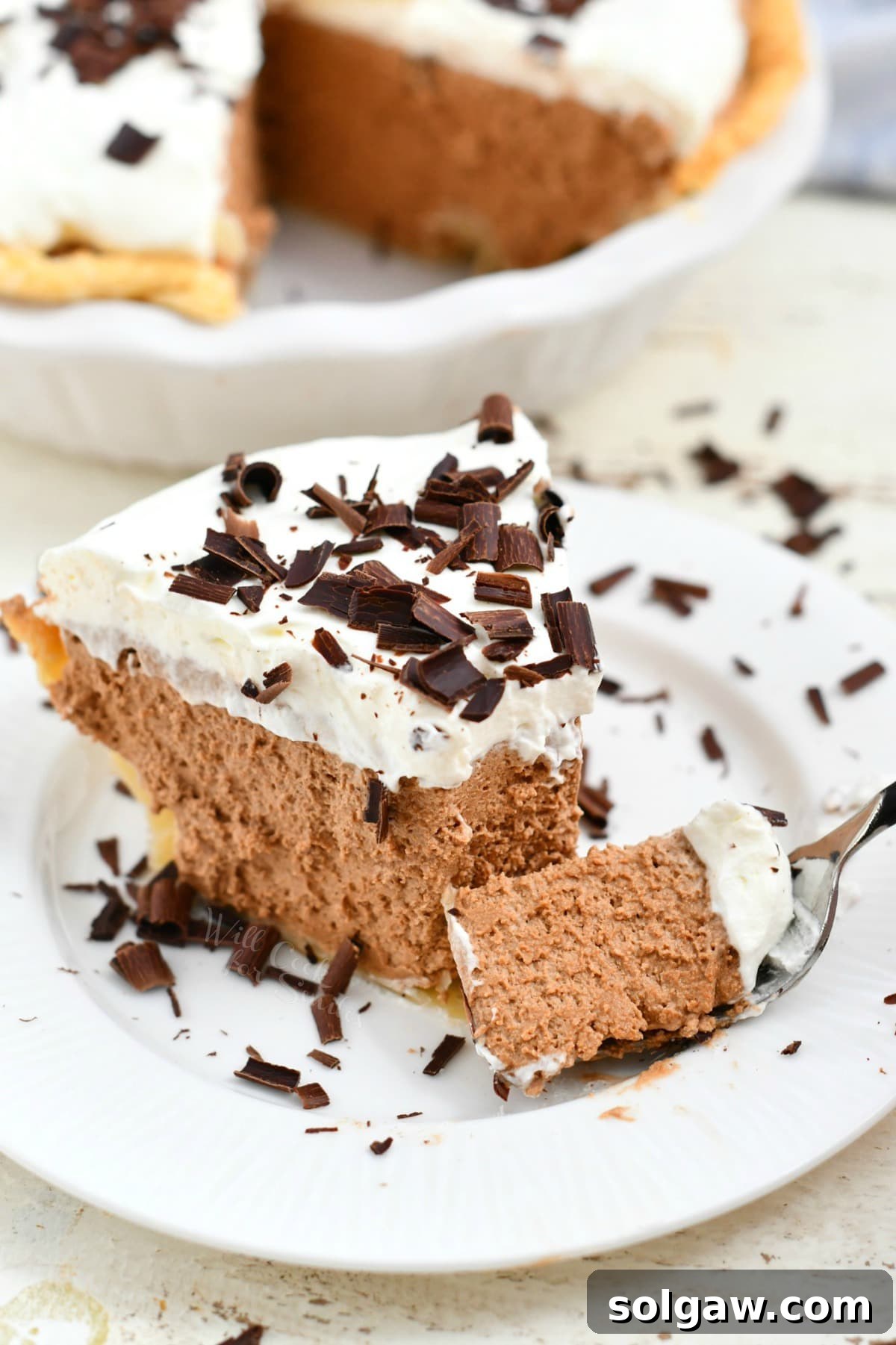forkful of creamy chocolate pie topped with whipped cream and chocolate shavings