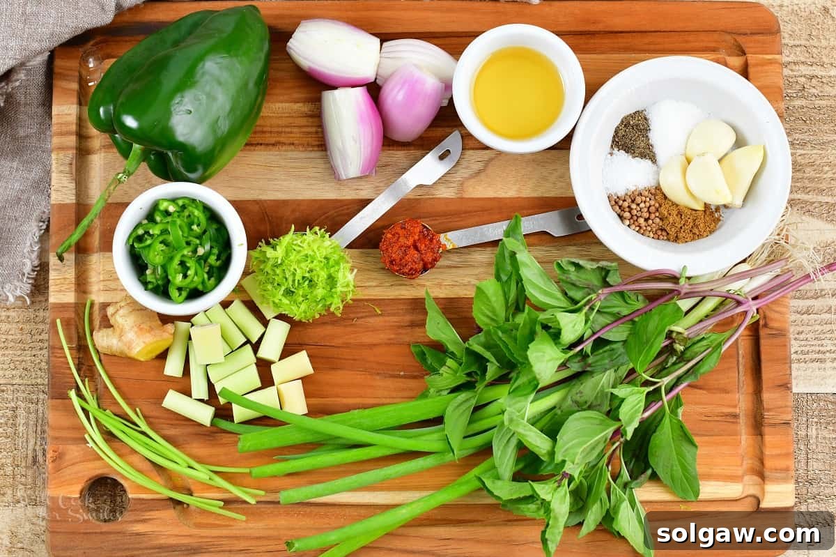 A selection of fresh, colorful ingredients for green curry paste laid out on a wooden cutting board, ready for preparation.