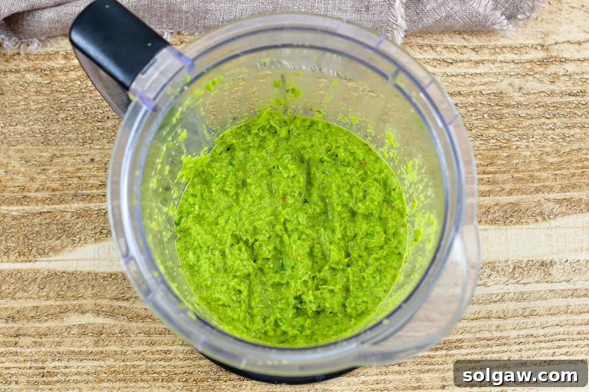 Smooth, vibrant green curry paste blended in a blender, showing its thick texture.