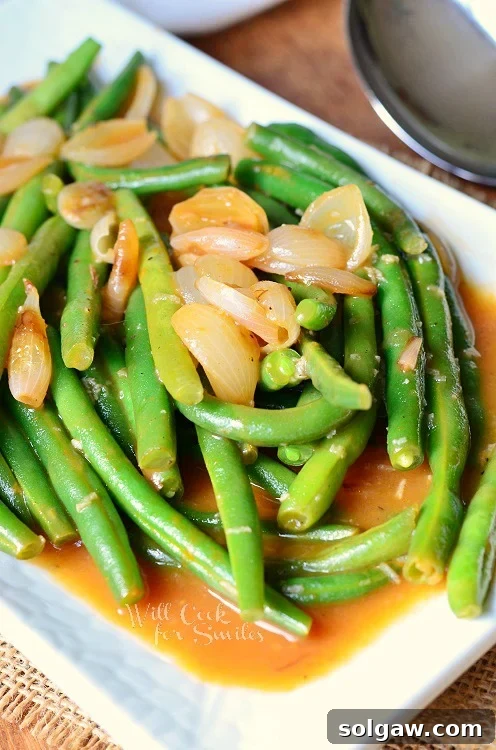 A vibrant plate of French Green Beans with caramelized pearl onions, ready to be served as a sophisticated holiday side dish.