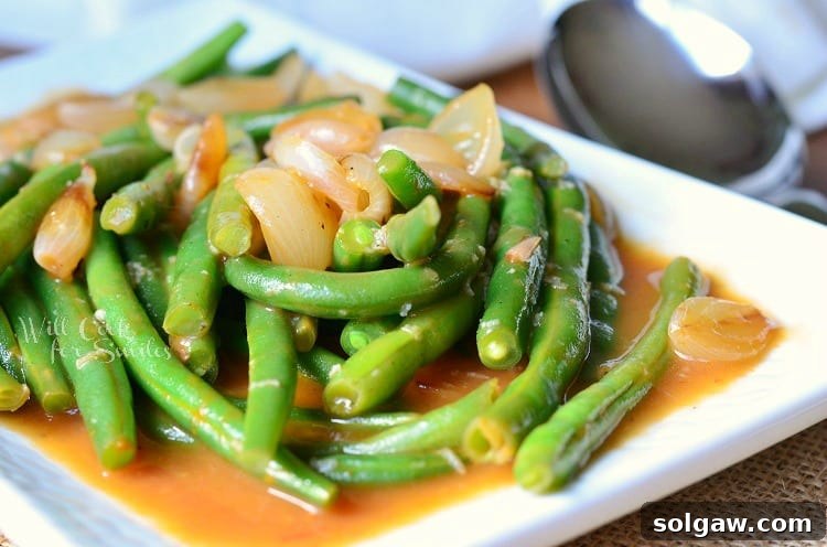 French Onion Green Beans on a white plate, showcasing the rich sauce and tender vegetables.
