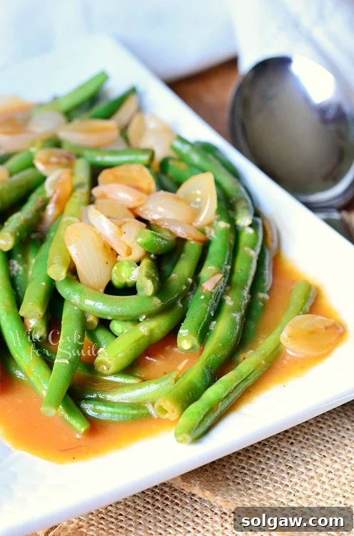 A final close-up of the delicious French Onion Green Beans, showcasing their vibrant color and rich sauce, served on a white plate.