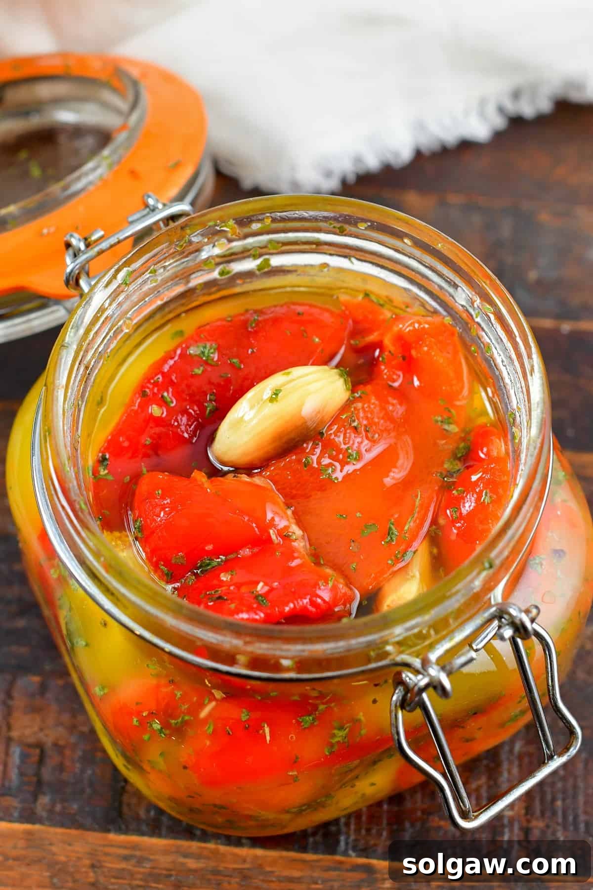 top view of roasted red peppers with garlic and herbs in a jar, ready for use