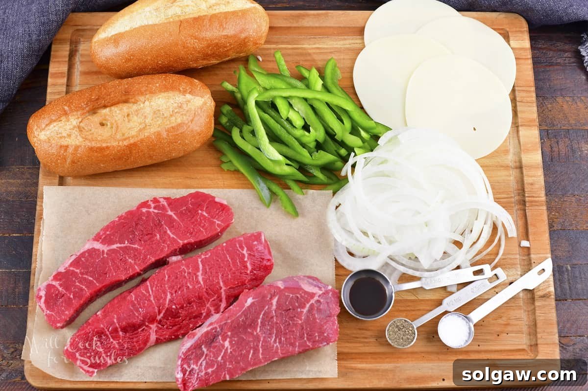 All the essential ingredients for making delicious Philly Cheesesteaks laid out on a cutting board, including steak, onions, peppers, and cheese.
