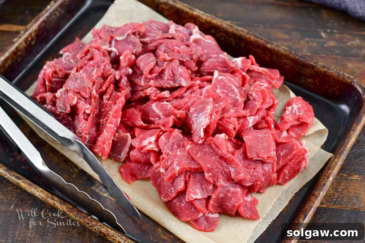 A pile of thinly sliced steak, perfectly prepped and seasoned, ready for cooking.