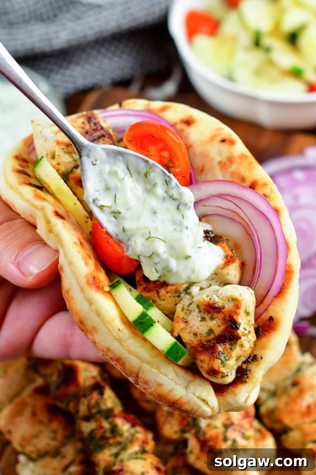 Chicken Souvlaki: Grill or Pan-Fry Your Way to Perfection 2 adding tzatziki sauce to chicken souvlaki in a pita