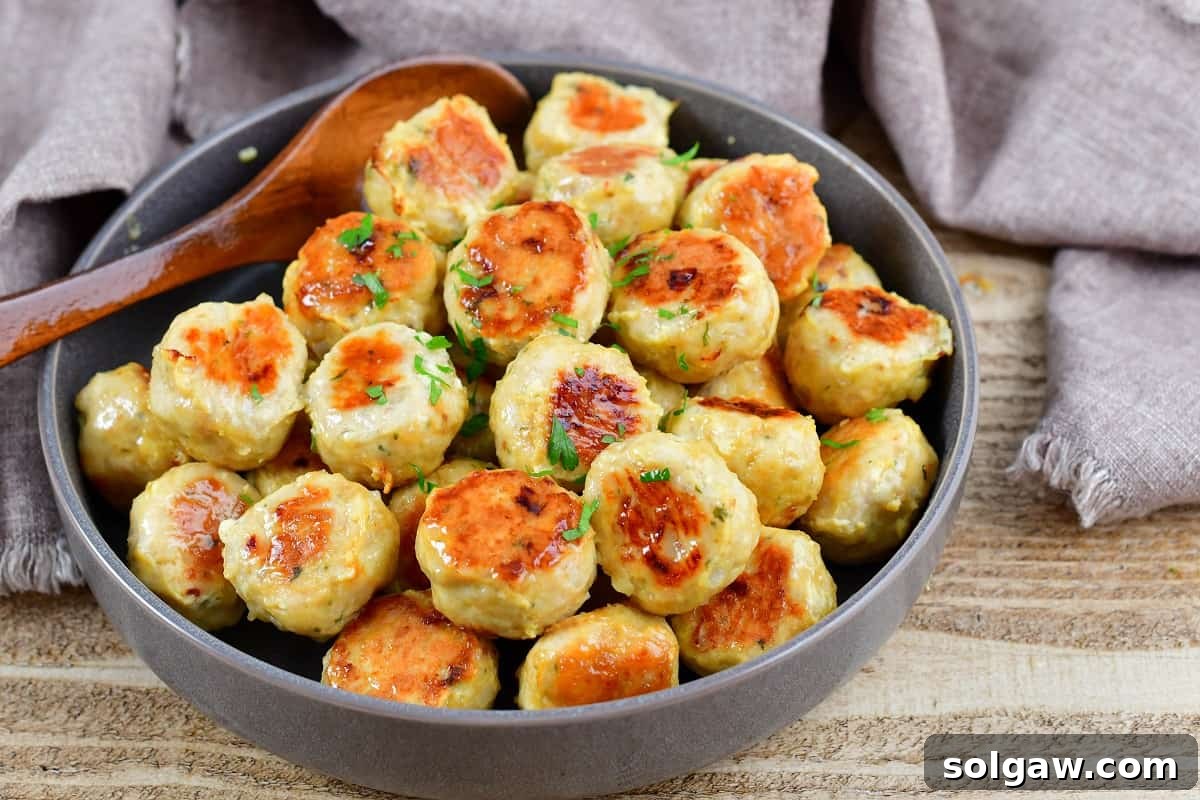 buttery chicken meatballs garnished with fresh herbs in a grey bowl, ready to serve