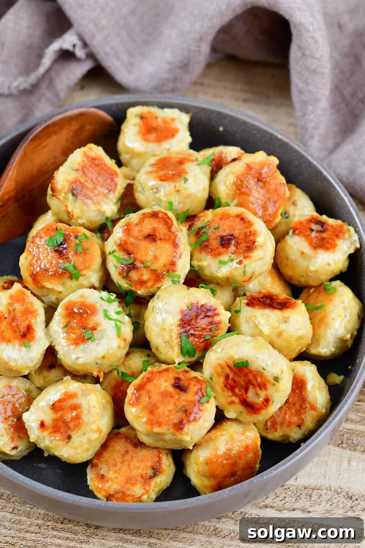top view of cooked chicken meatballs in a bowl with fresh herbs, ready to be enjoyed