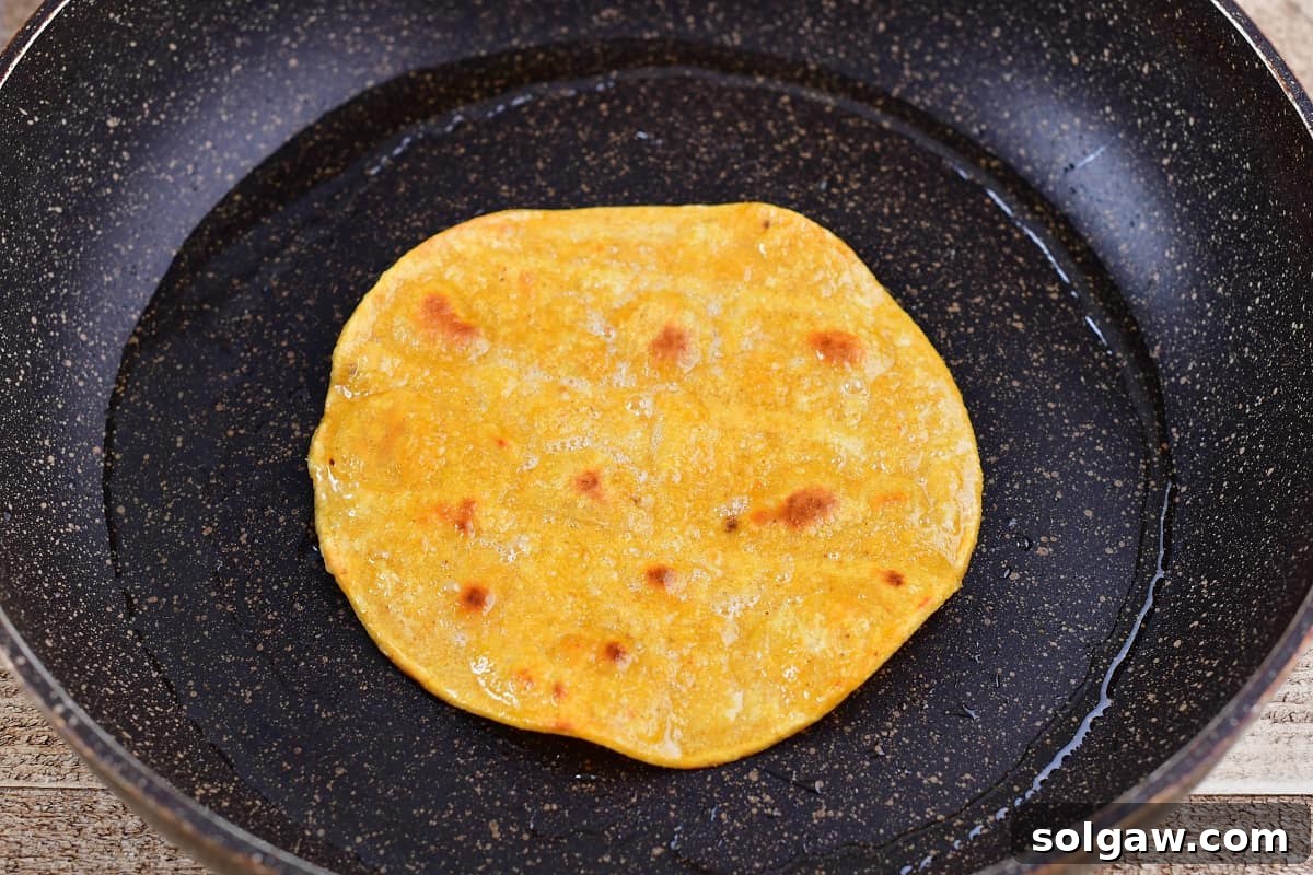 Cooking corn tortillas in a hot pan until lightly golden and crispy.