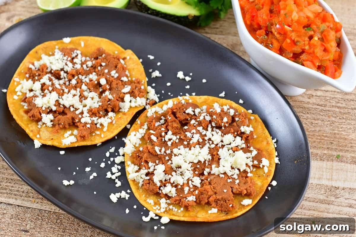 Crispy corn tortillas topped with a generous layer of refried beans and crumbled queso fresco.