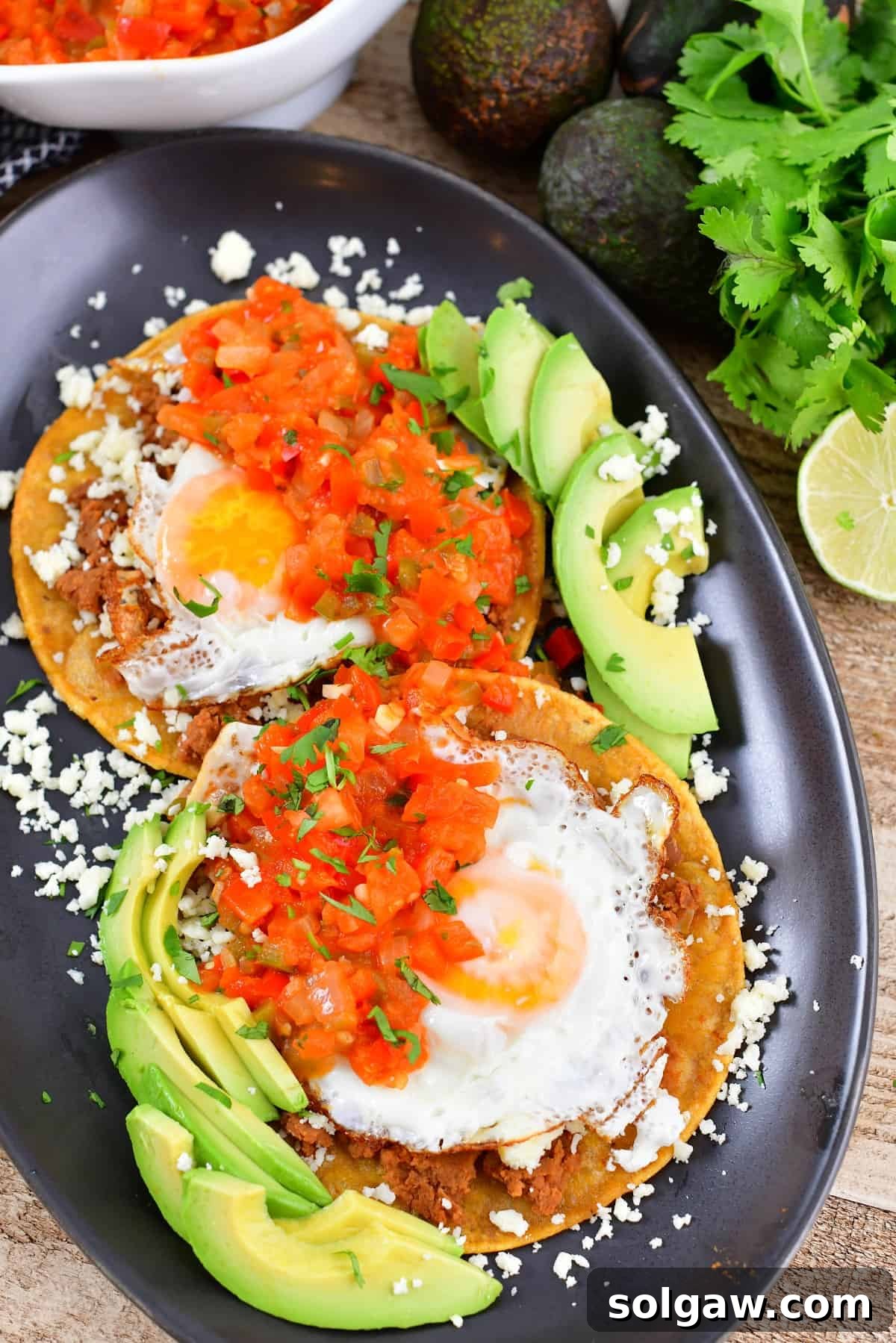 Top view of a beautifully plated Huevos Rancheros with assorted toppings, including avocado slices and fresh cilantro.
