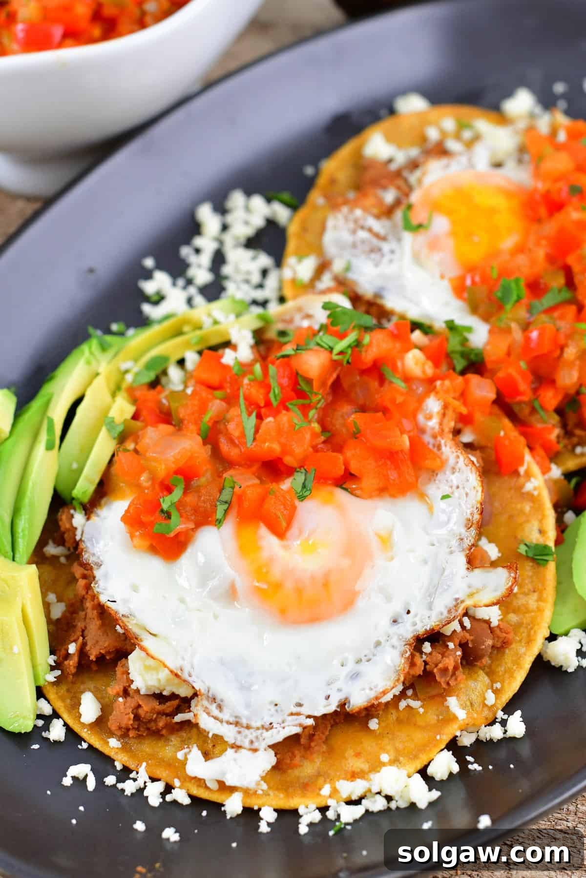 Closeup view of perfectly cooked eggs over tortillas and tomato salsa.
