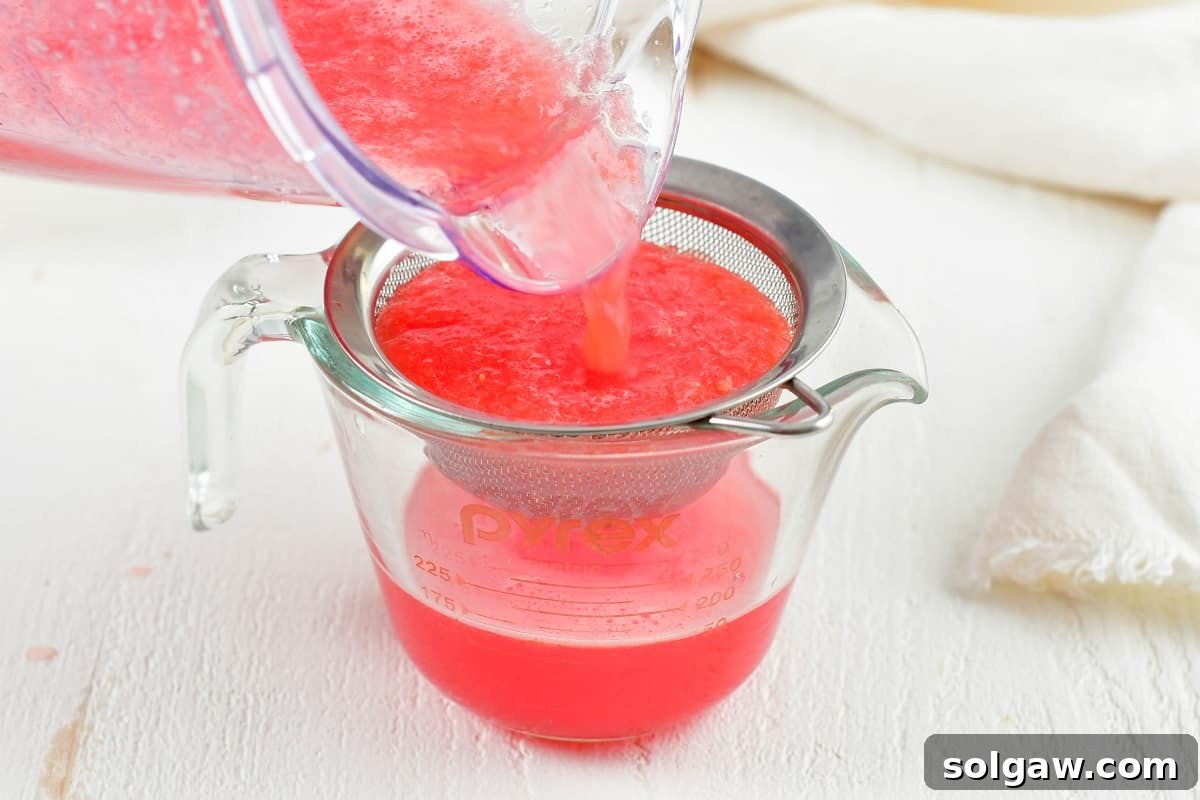 Straining watermelon juice through a fine mesh sieve