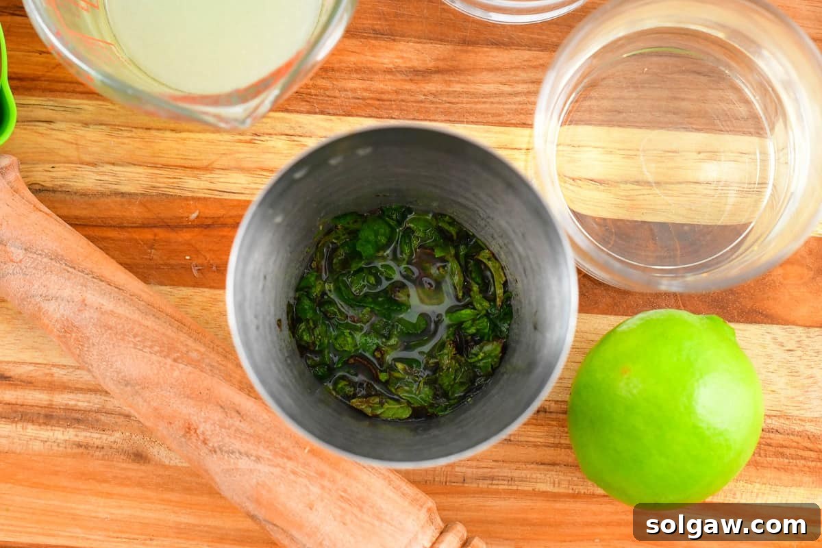 Mashed mint leaves and lime juice in a cocktail shaker