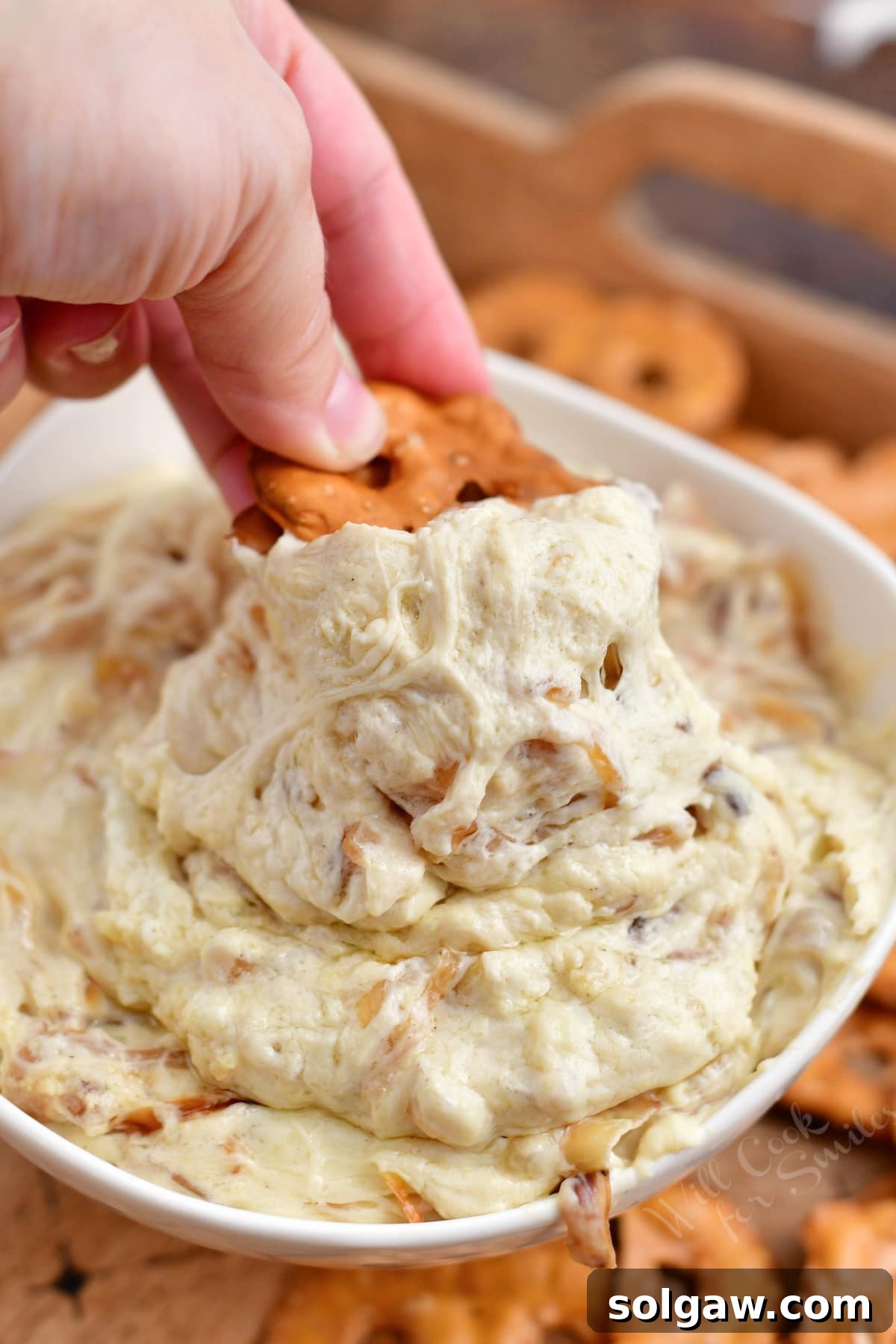 pretzel chip being dipped into a bowl of French onion dip