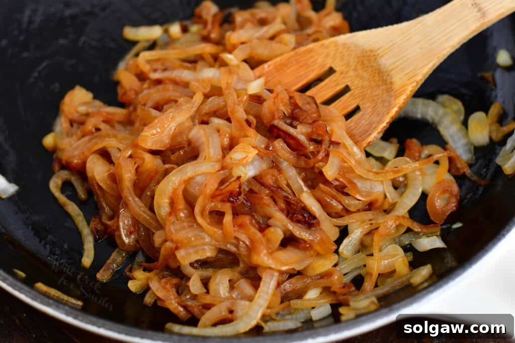 wooden spoon stirring caramelized onions in a skillet