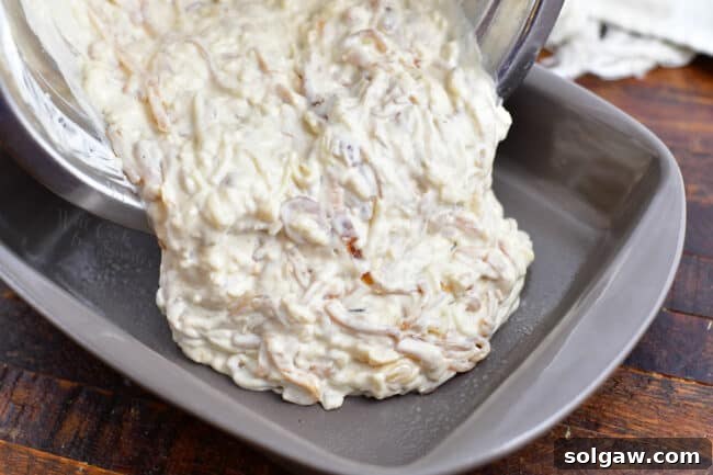 French onion dip being poured into a greased baking dish
