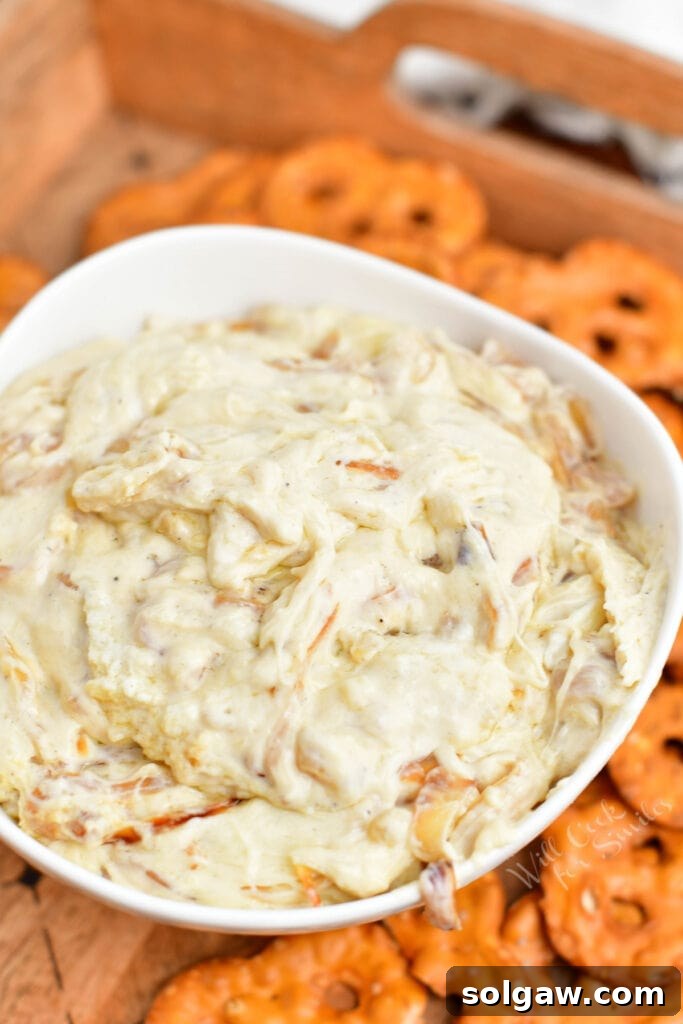 bowl of white dip surrounded by pretzel chips