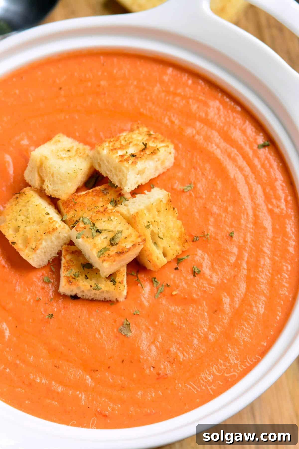 A comforting bowl of rich, creamy tomato bisque garnished with homemade croutons, perfect for a cozy meal.