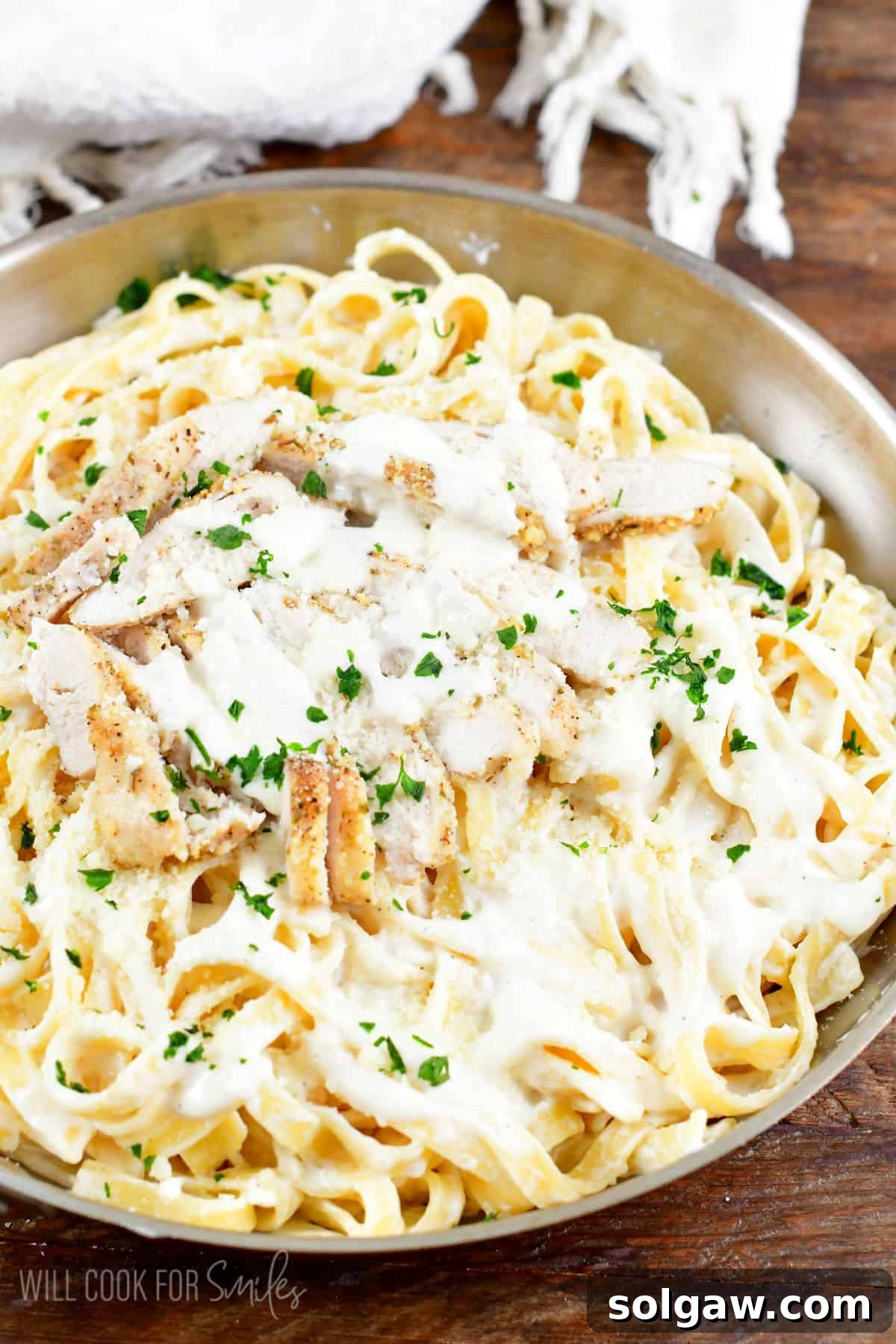 Chicken alfredo in a pan on a wood surface.