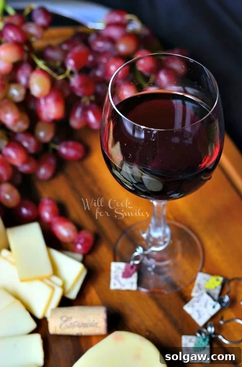 The Art of Wine and Cheese Pairing 4 Cheese on a cutting board with red wine in a glass and grapes and cheese on a cutting board