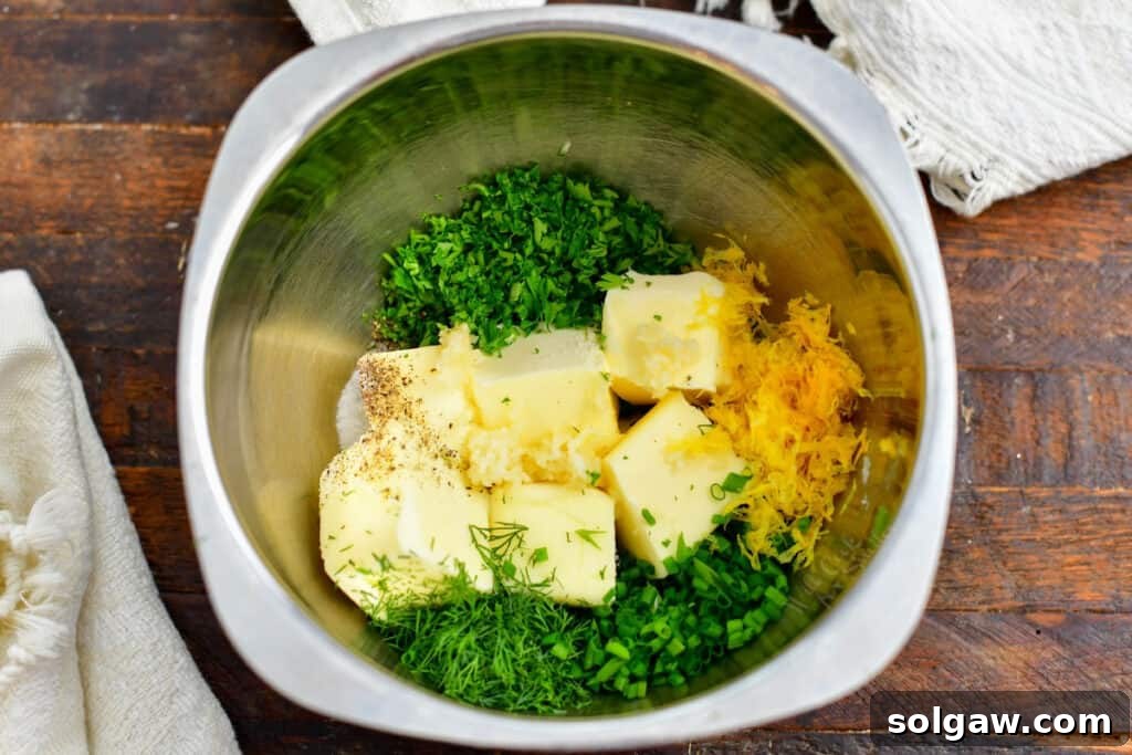 Cubes of softened butter mixed with finely chopped fresh herbs and garlic in a mixing bowl.