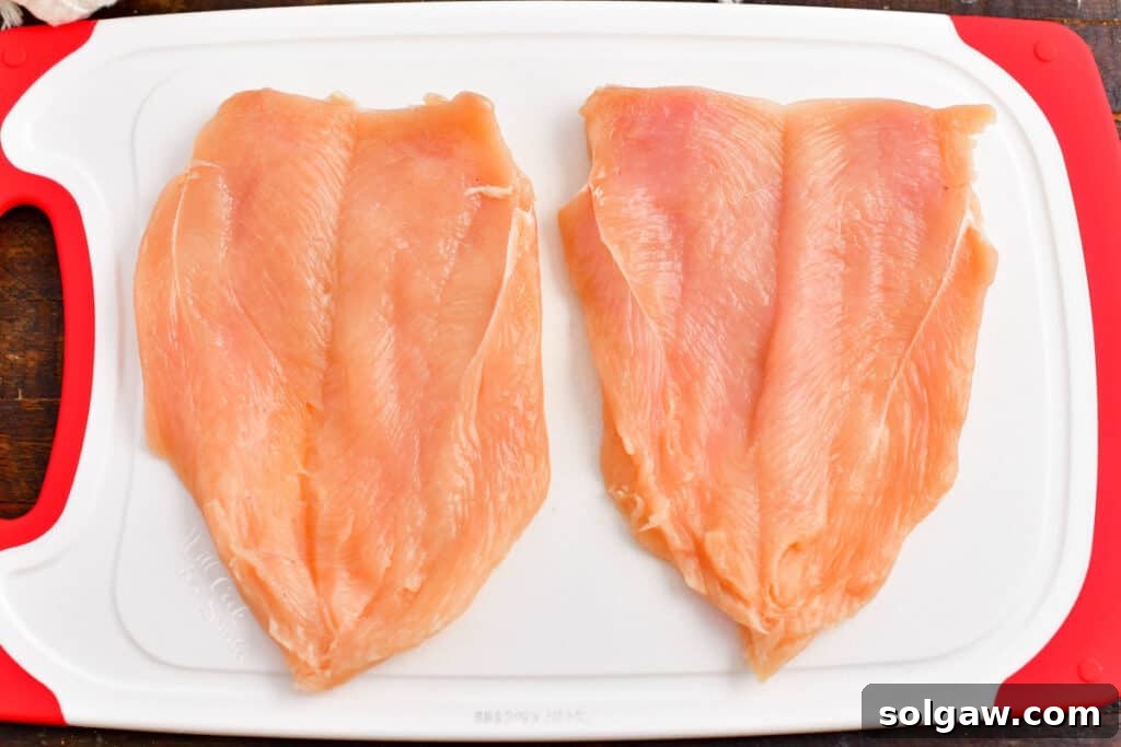 Raw chicken breast perfectly butterflied on a cutting board, opened flat like a book.