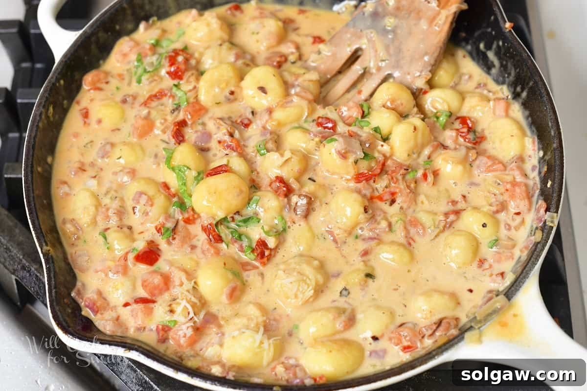 The finished creamy tomato gnocchi dish, perfectly sauced with pancetta and basil, ready to serve.