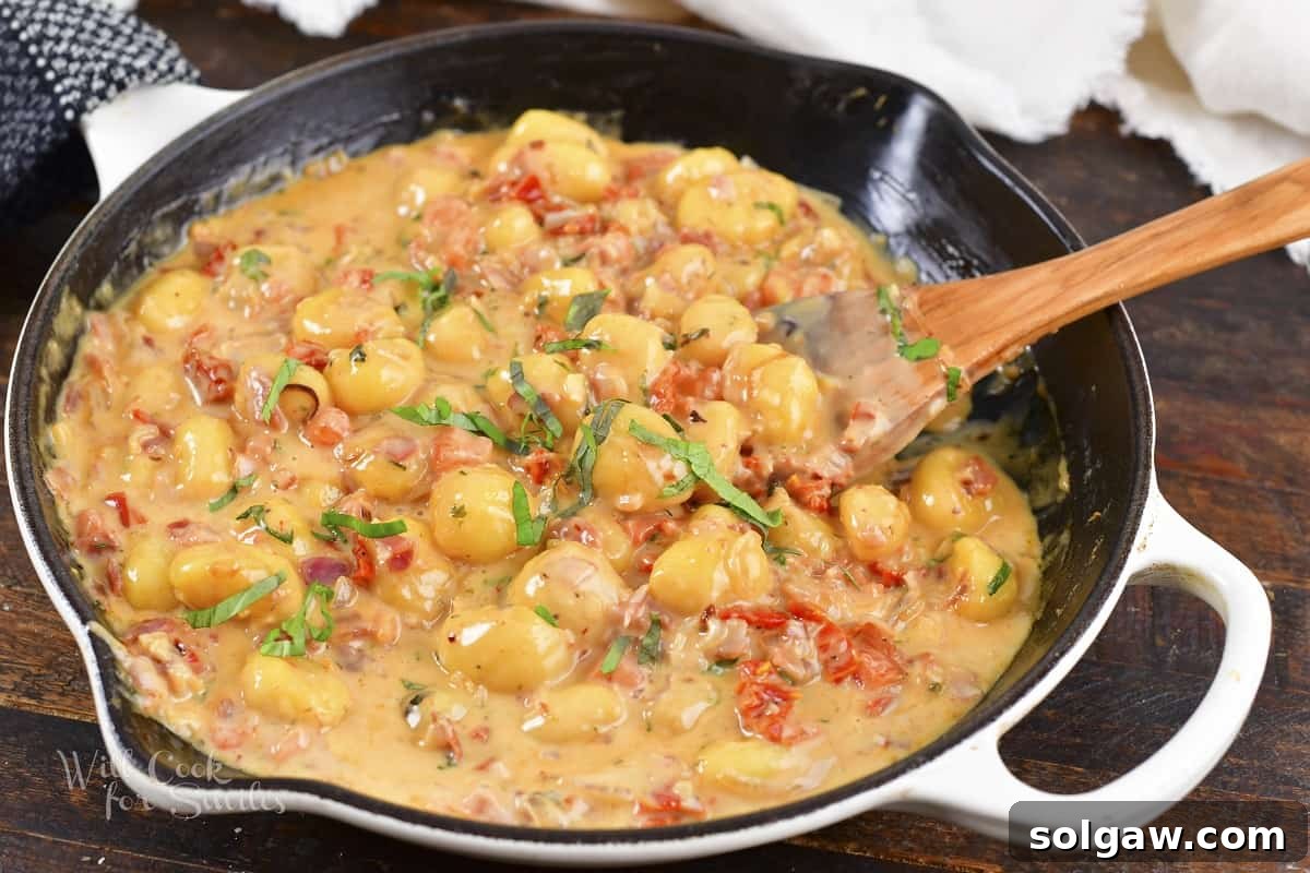 A close-up shot of the cooked creamy tomato gnocchi in a pan, showcasing its rich texture and vibrant colors.