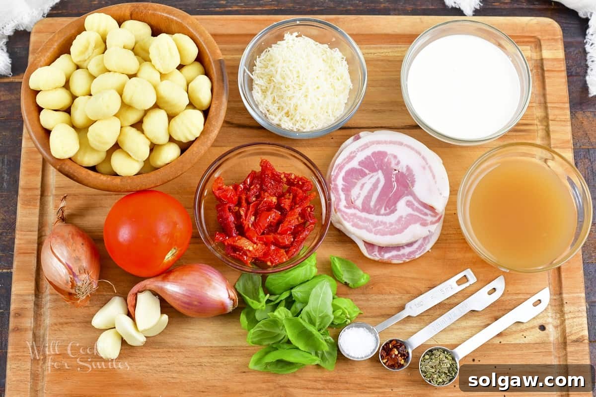 A flat lay photograph showcasing all the fresh and vibrant ingredients needed for creamy tomato gnocchi, including tomatoes, basil, gnocchi, pancetta, and shallots.