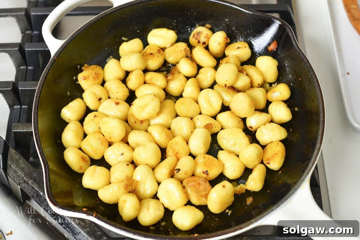Searing potato gnocchi in a hot pan until golden brown and slightly crispy on the outside.