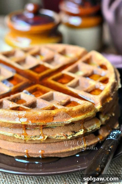 Gingerbread Waffles with syrup over the top on a brown plate
