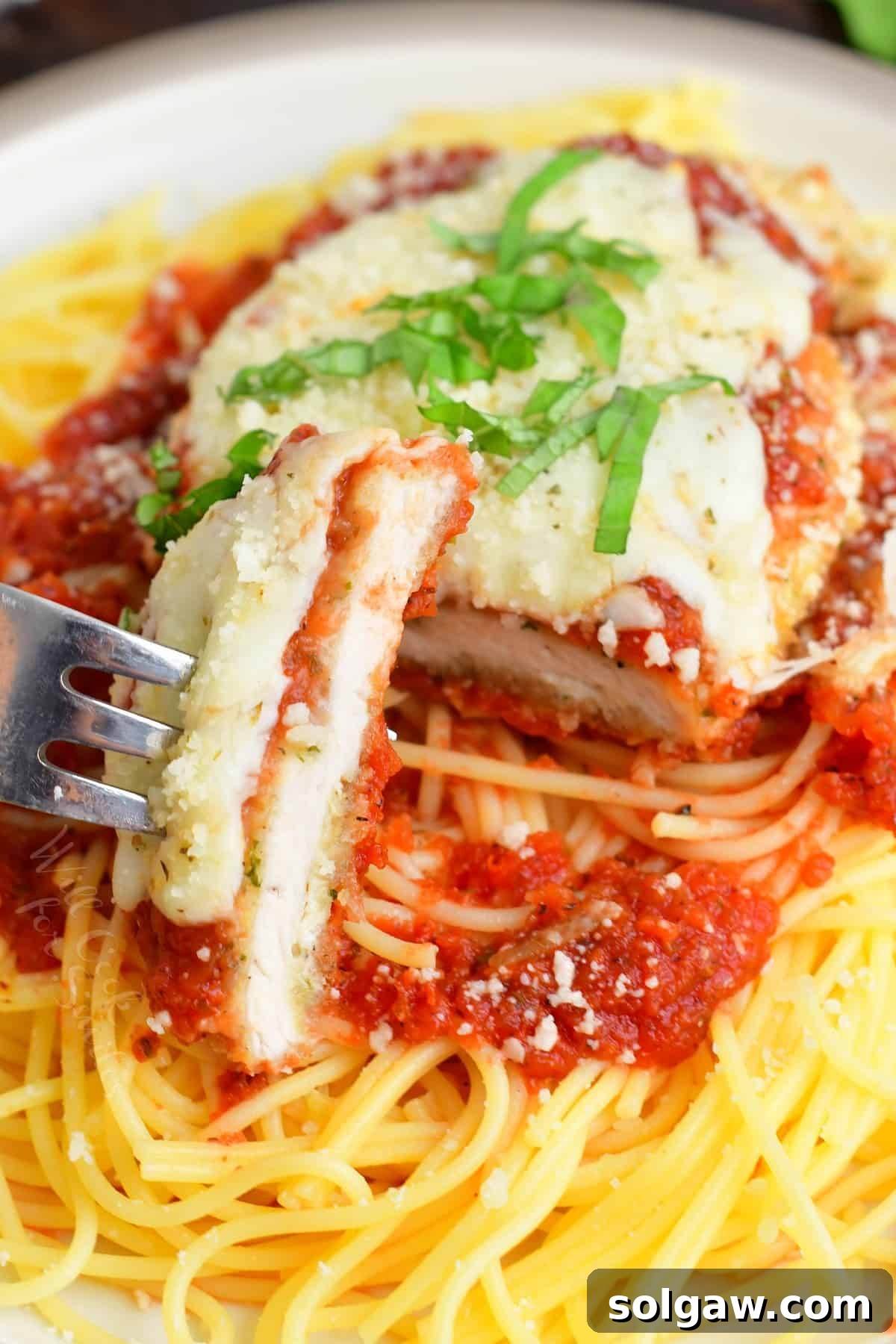 chicken parmesan on top of spaghetti with a sliced cut off