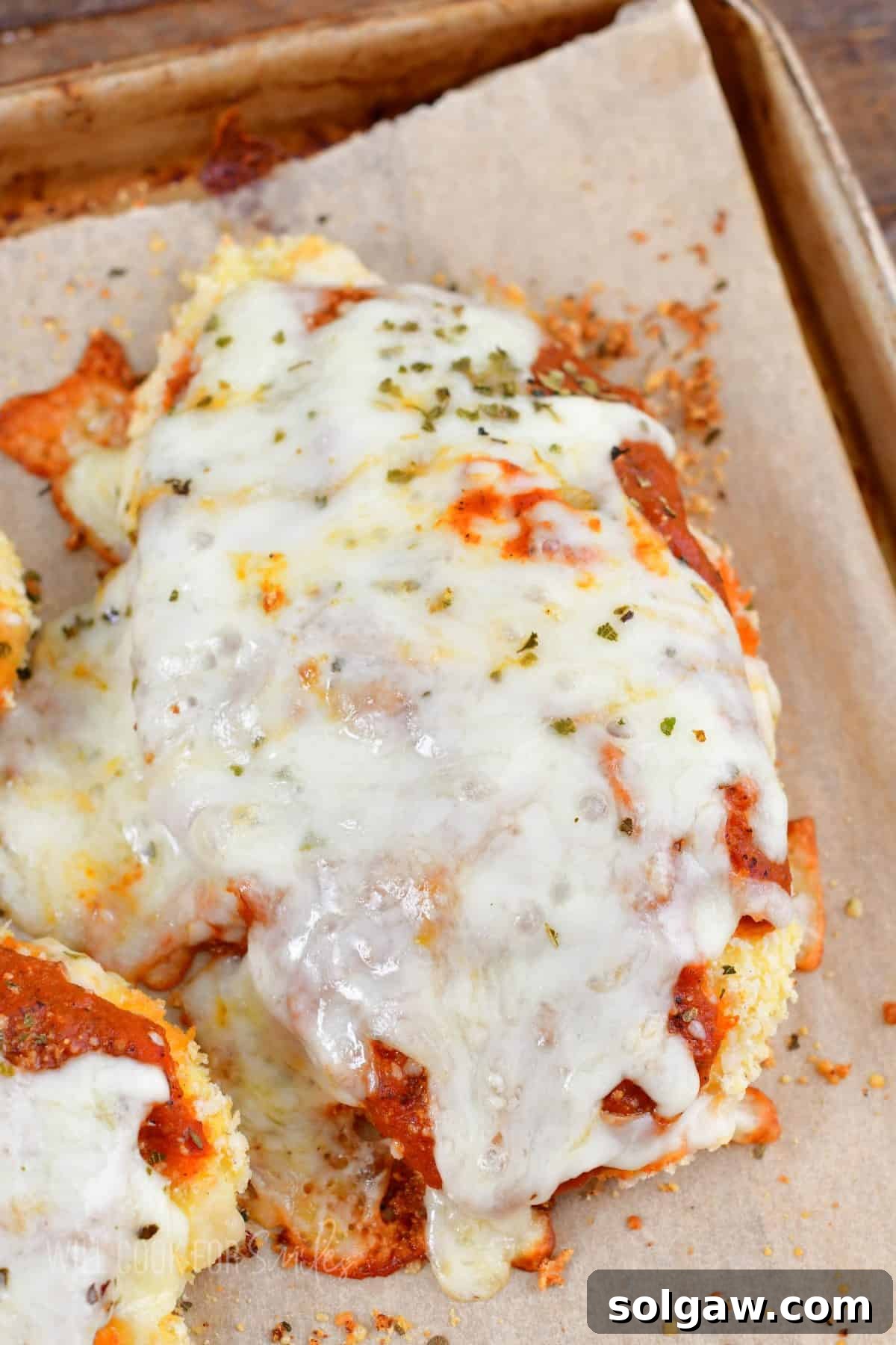 closeup of one chicken parmesan piece on a baking cheese.