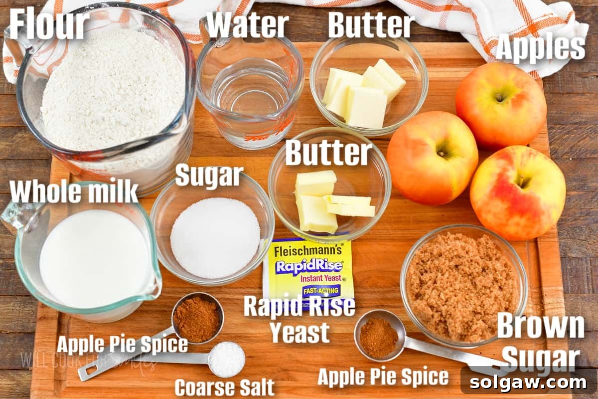 Labeled ingredients for making apple pie monkey bread, including apples, flour, butter, spices, and yeast, arranged on a wooden cutting board.